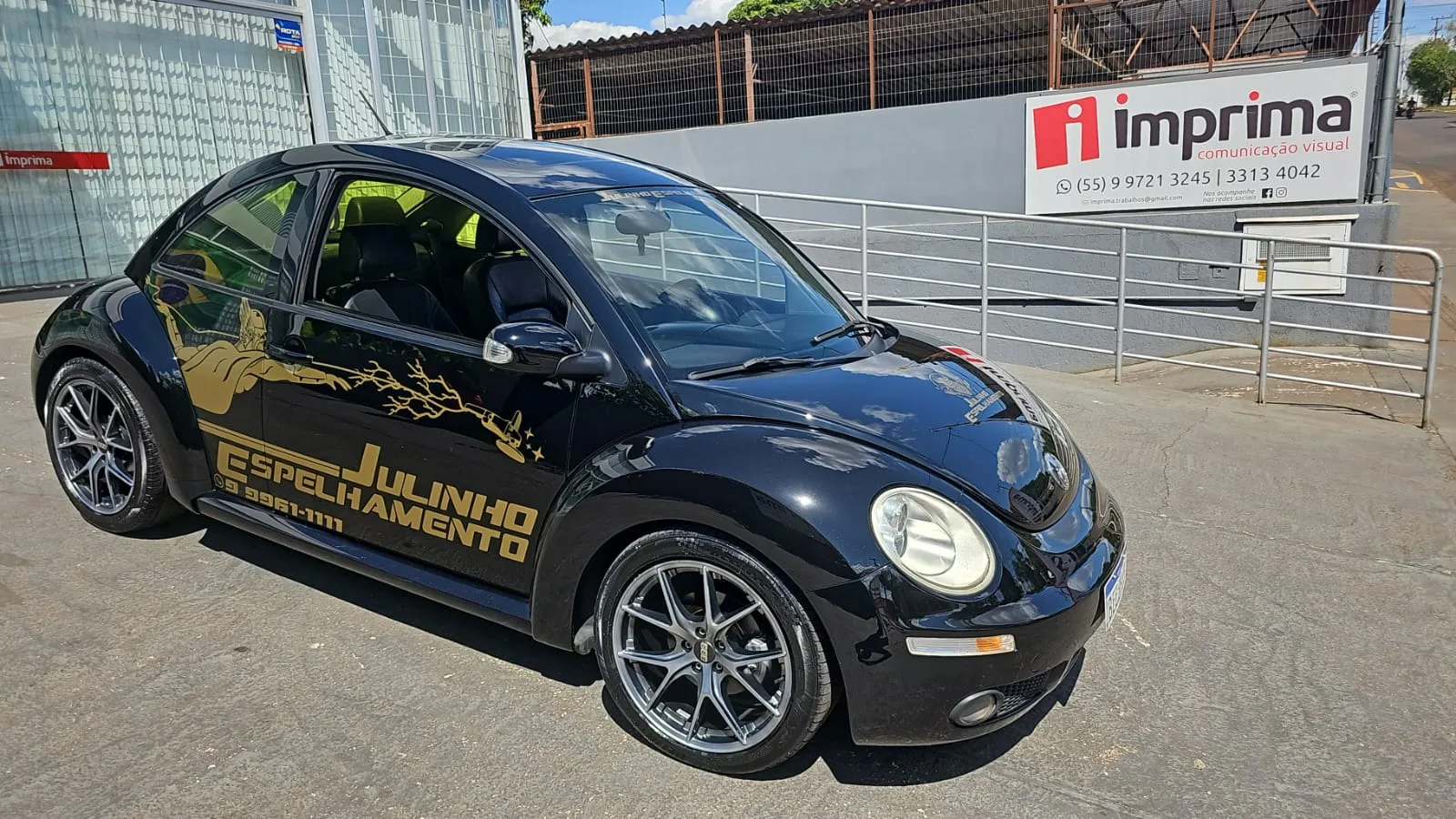 Fusca preto com adesivos dourados da Julinho Espelhamento em frente à loja da Imprima Comunicação Visual